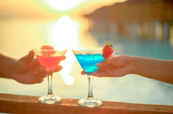 an escort and her client clinking glasses in front of a Puerto Banus sunset