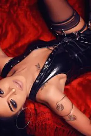 Agatha Shemale lay back on her bed wearing a black PVC dress
