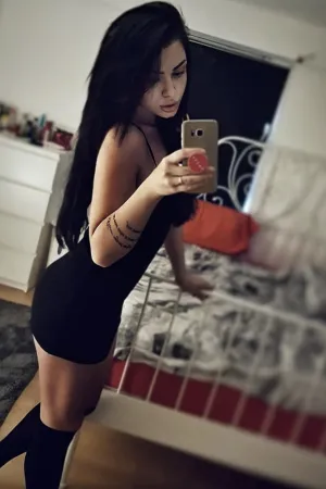 Kelly wearing a tight black pencil dress in her bedroom