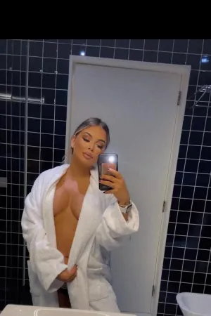 Bia wearing an open white dressing gown showing off her cleavage