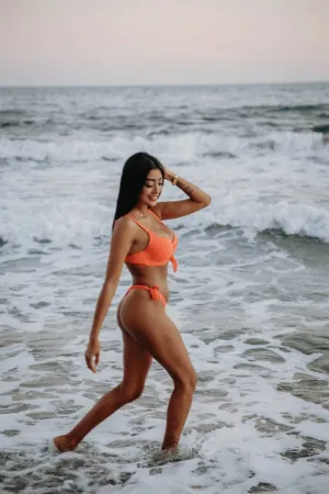 Maya wearing an orange bikini on the beach