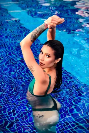 Isabela getting out of the pool while wearing a set of dark green bikini