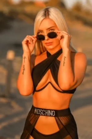 Michelle standing in a set of black swimwear adjusting her sunglasses