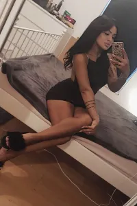 Kelly taking a selfie on her bed showing off her sexy legs as she wears a short black dress